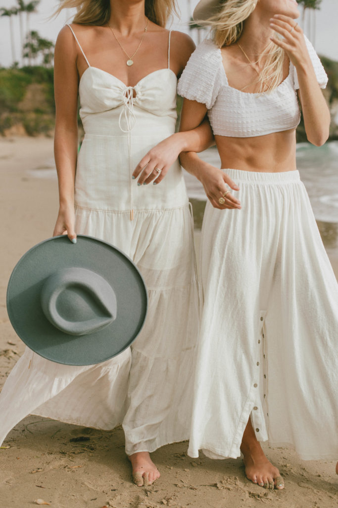 portrait of two models white, boho outfits at the beach