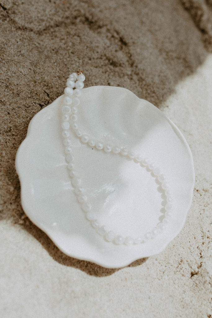 picture of pearl necklace laying on white sea shell on the beach