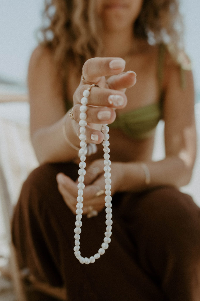 close up portrait of model holding saltee hawaii's pearl necklace
