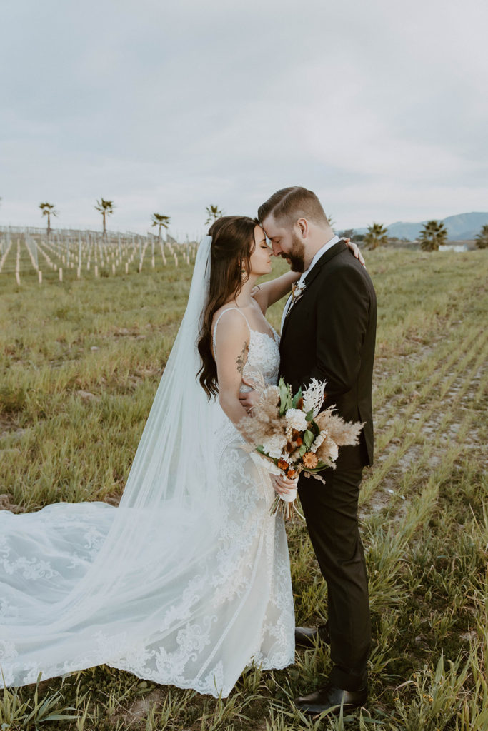 picture of the bride and groom leaning into one another with green scenery in the back