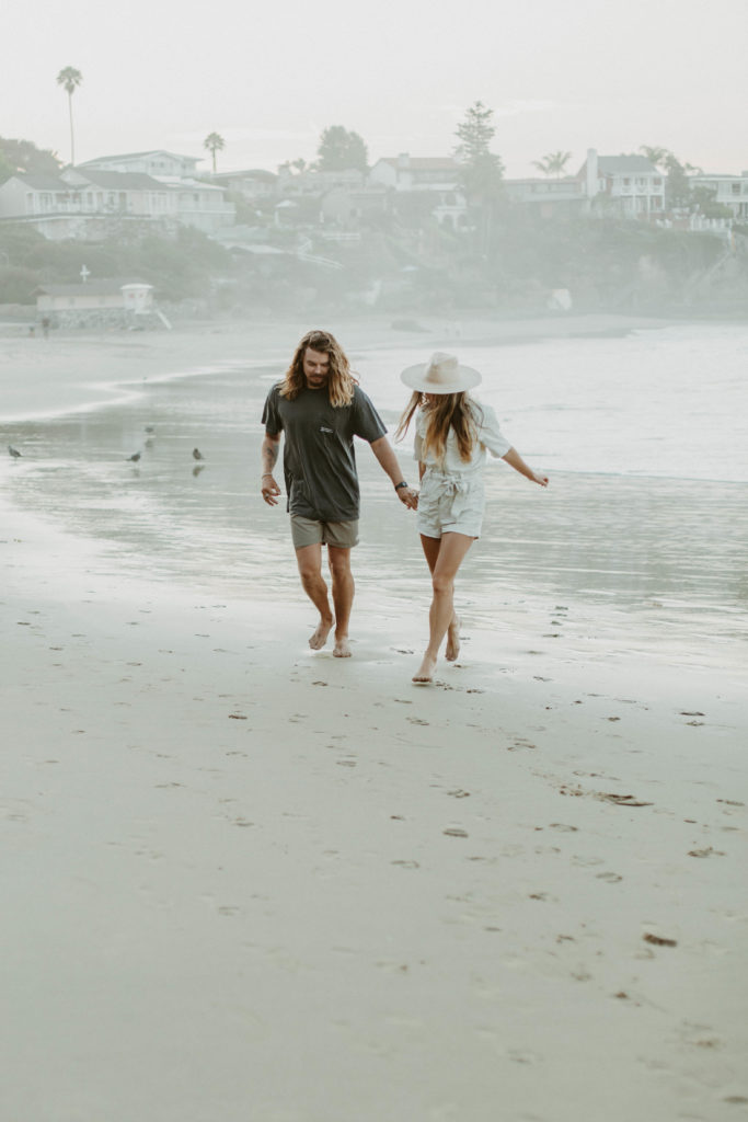 bree and brock are walking along the beach holding hands