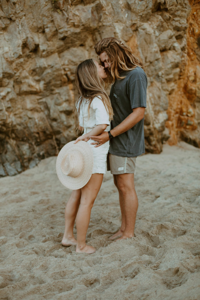 the couple is leaning into kiss while standing on the beach