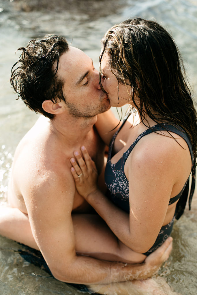 dani and her husband kissing while sitting in the water