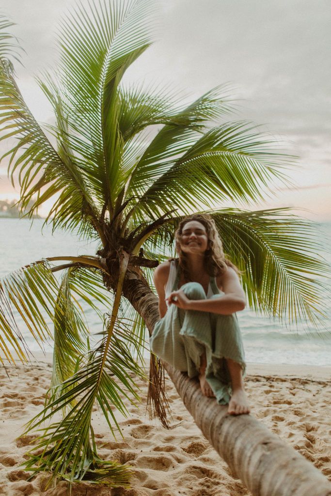 danielle sitting on a palm tree and smiling
