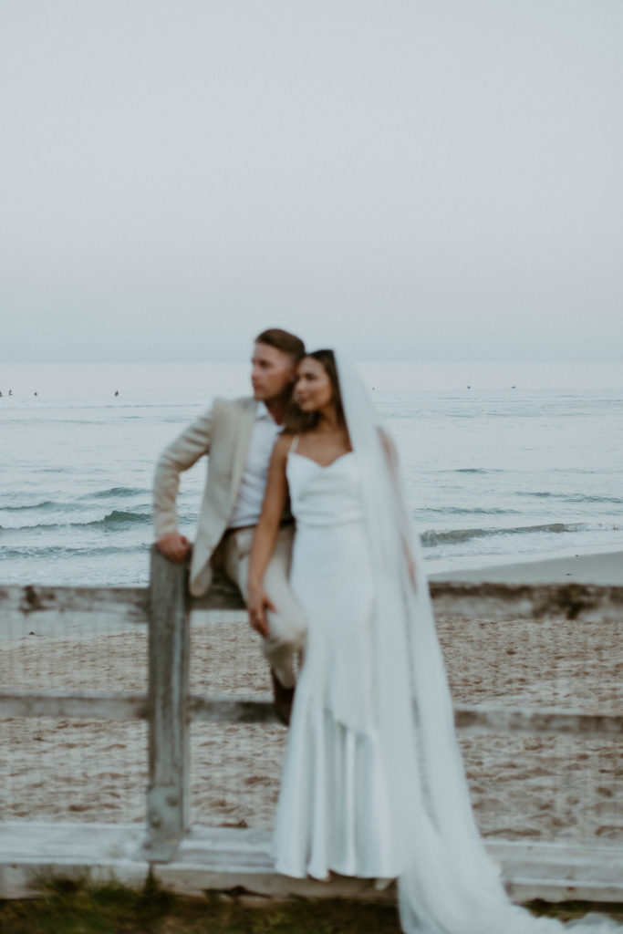 blurry candid of the bride and groom standing on a beach pier