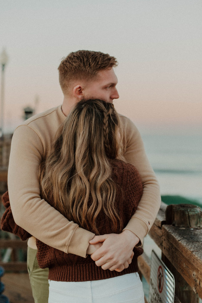 shot of the couple hugging eachother and looking off at the ocean