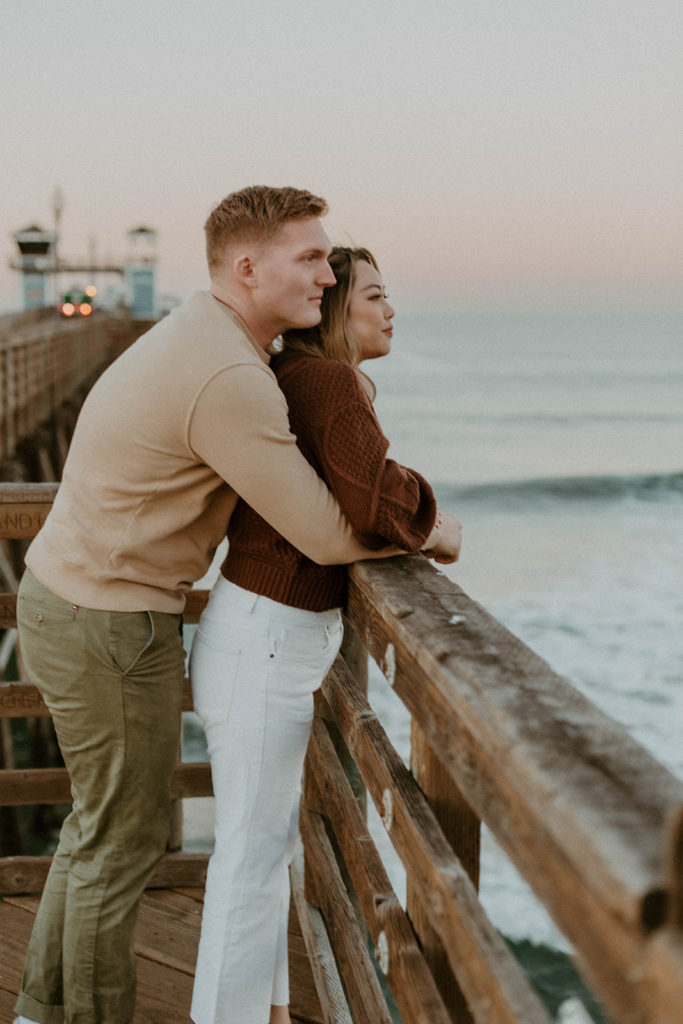 shot of the couple both leaning against the pier
