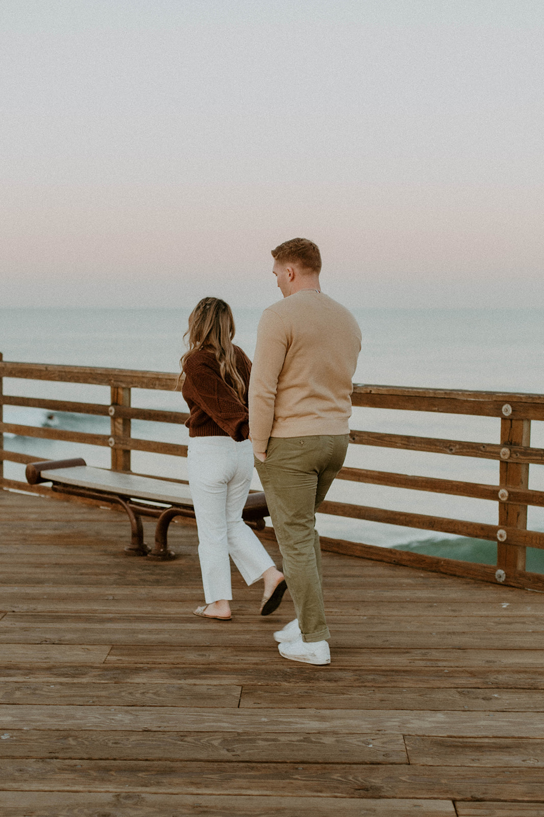 couple is holding hands and walking away from camera