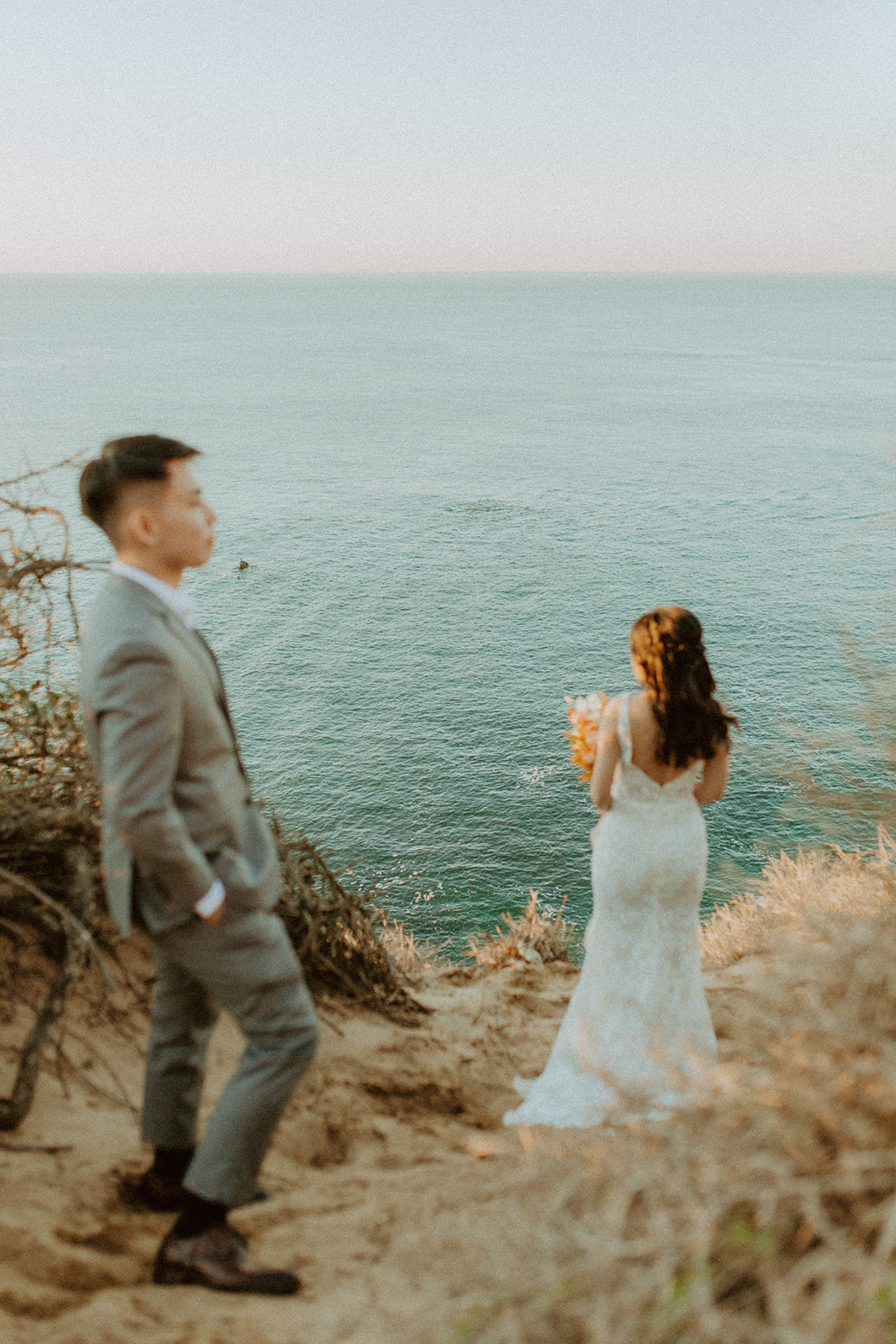 editorial shot of the bride and groom standing on the cliffside
