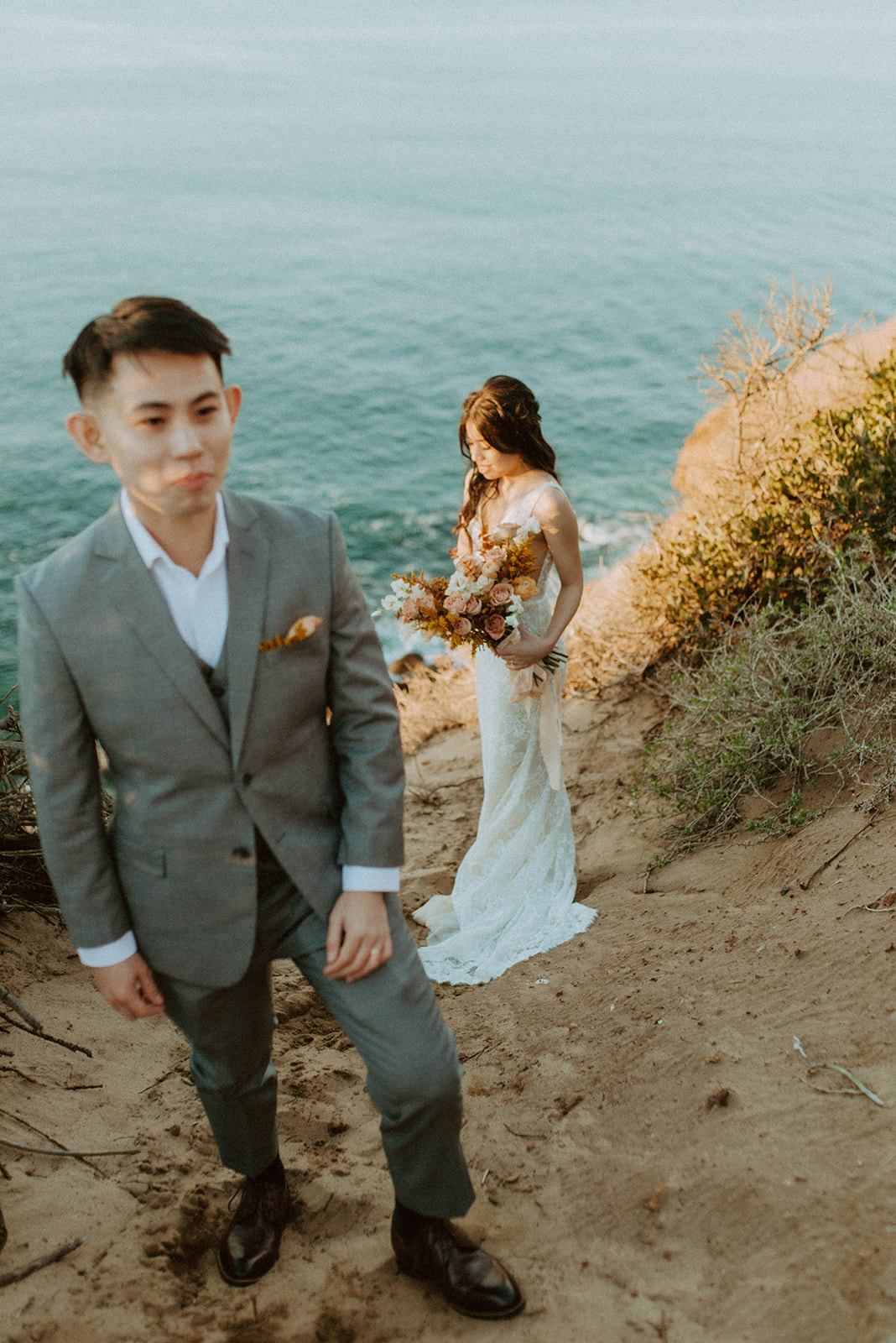 editorial shot of the groom standing in front of the bride who is in focus