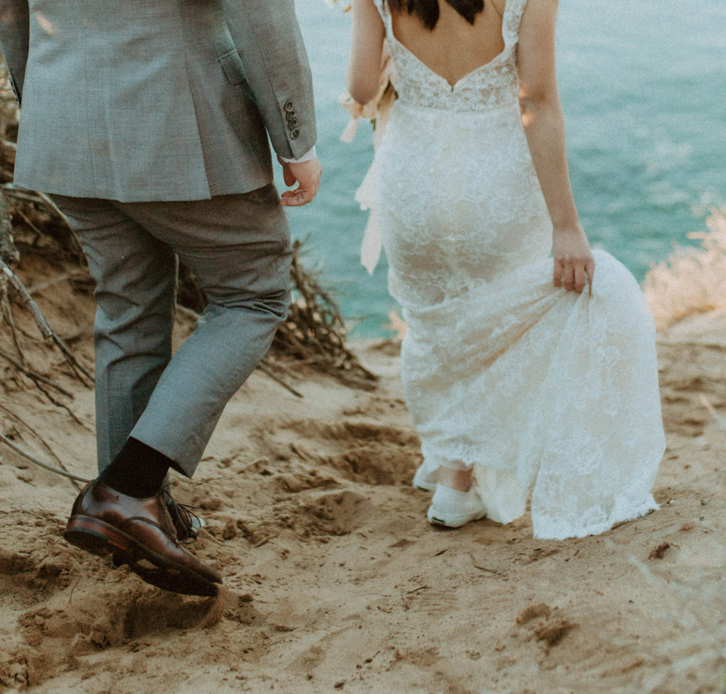 shot of the bride and groom walking down the cliffside