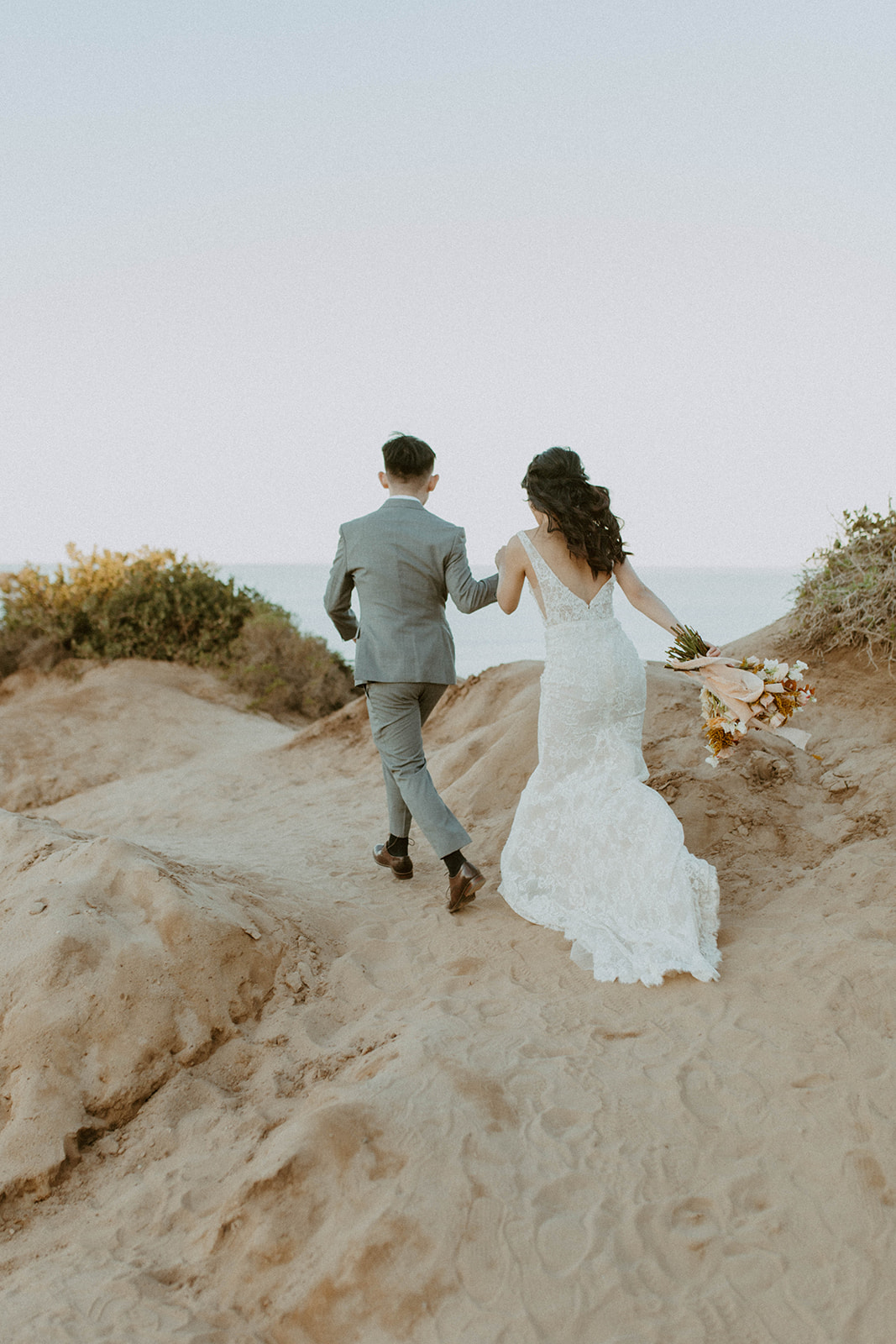 couple is holding hands and running towards the ocean